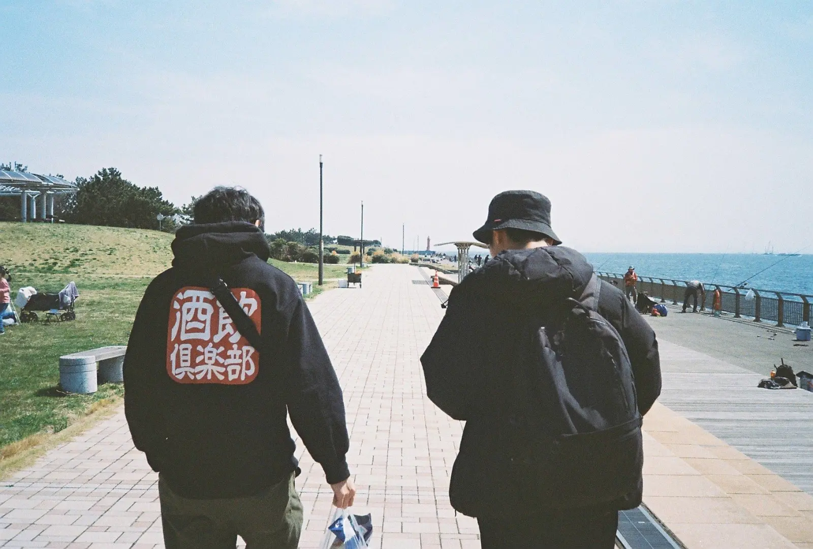 海沿いの道を歩くふたりの後ろ姿