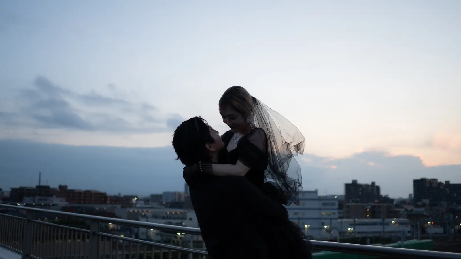日が落ちる街を背に抱き合うふたり