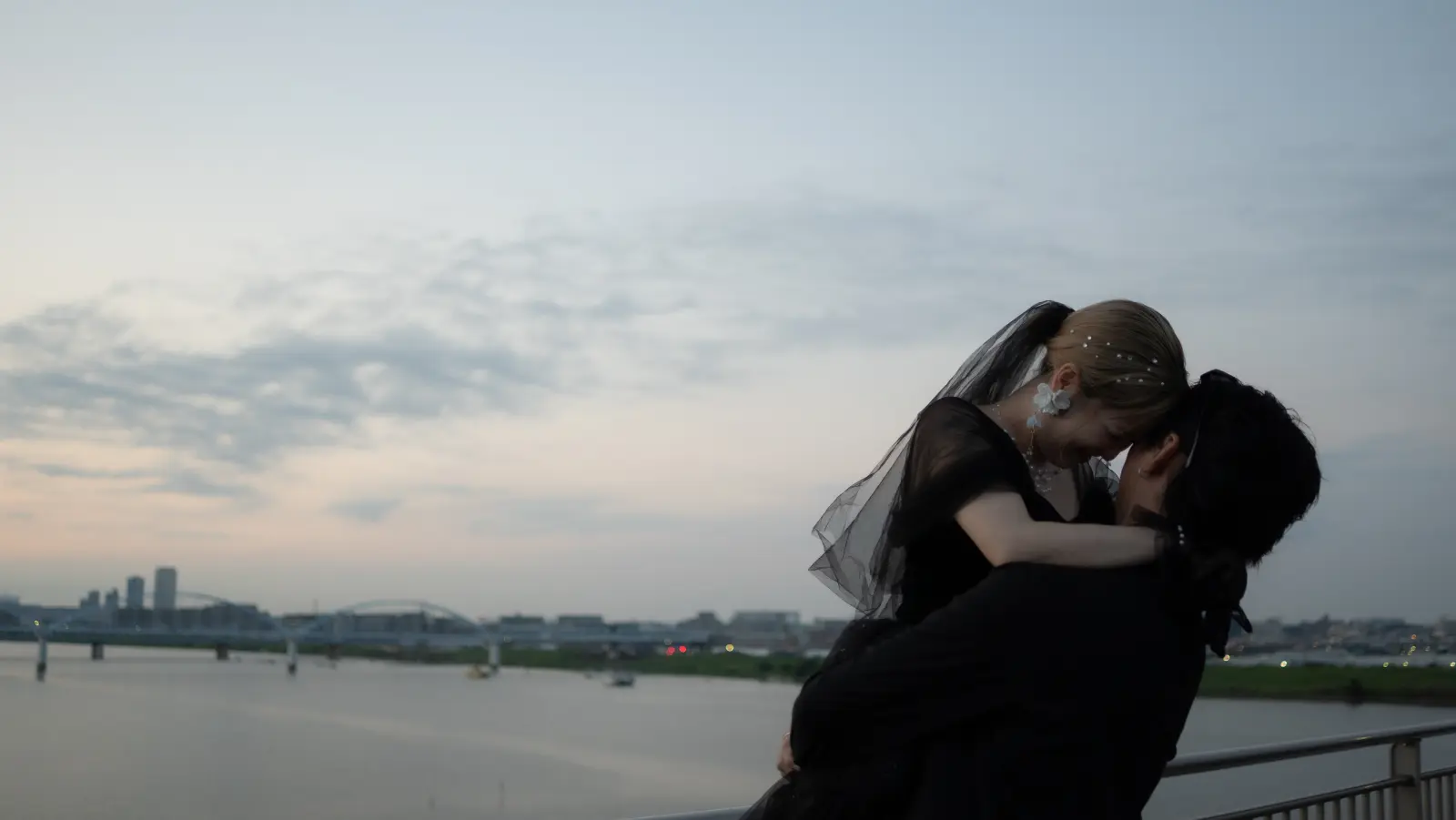 川辺の夕景のなかで抱き合うふたり