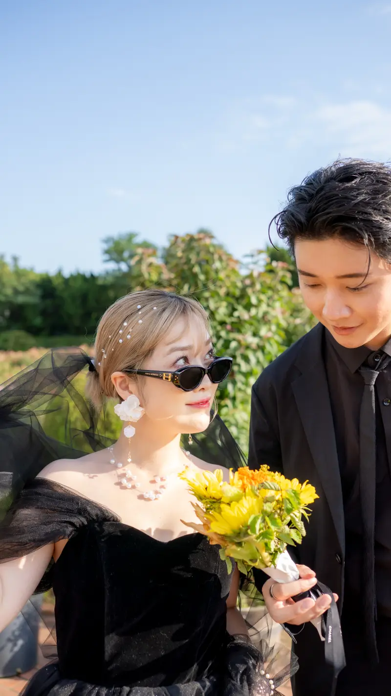 サングラスとヴェールの女性が、ひまわりの花束を抱える